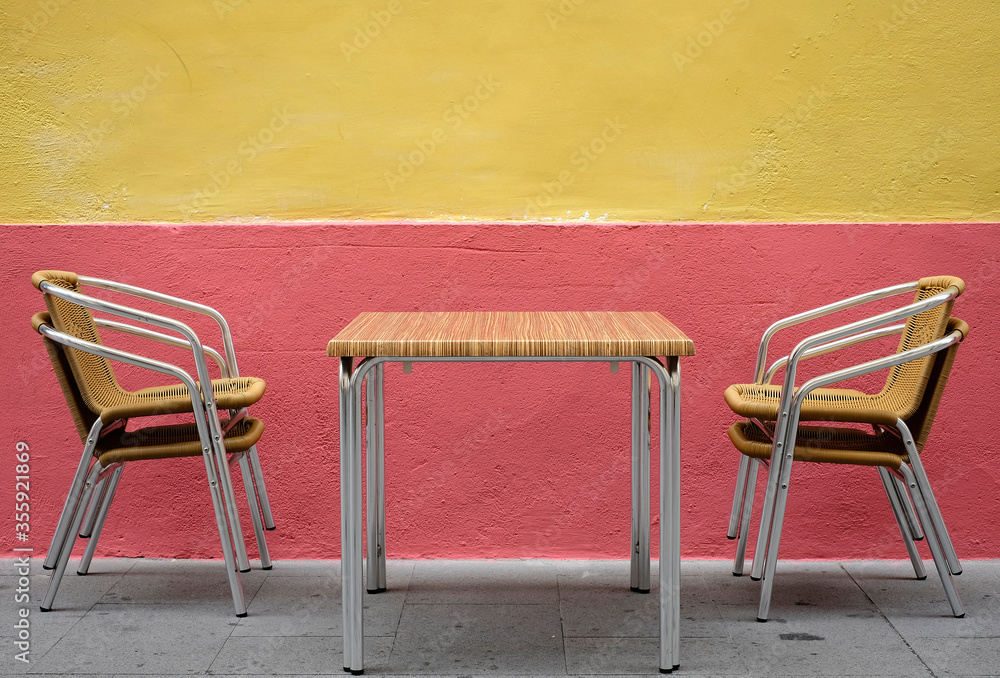 Mesa y sillas de terraza sobre pared roja y amarilla Stock Photo