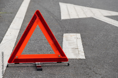 Emergency red warning triangle on the road sign with white traffic line