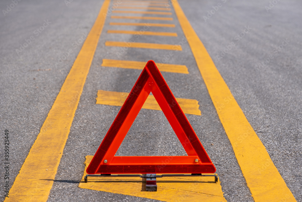 Emergency red warning triangle on the road sign with yellow traffic line