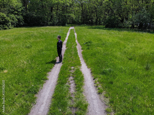 Man on double path at green clearing with trees around