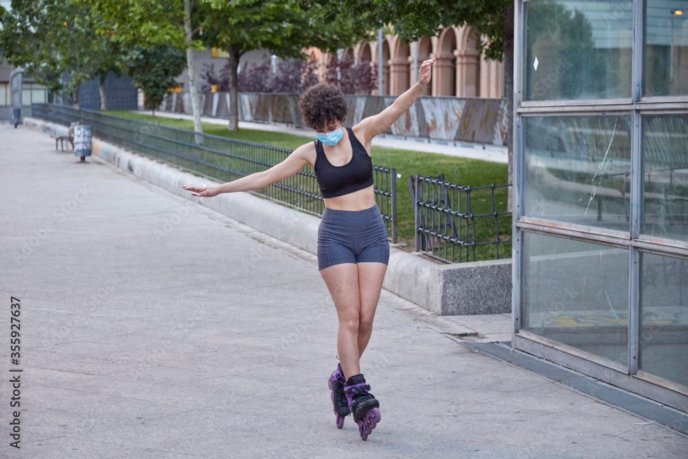 Latin girl skating on inline skates protecting herself with a face mask