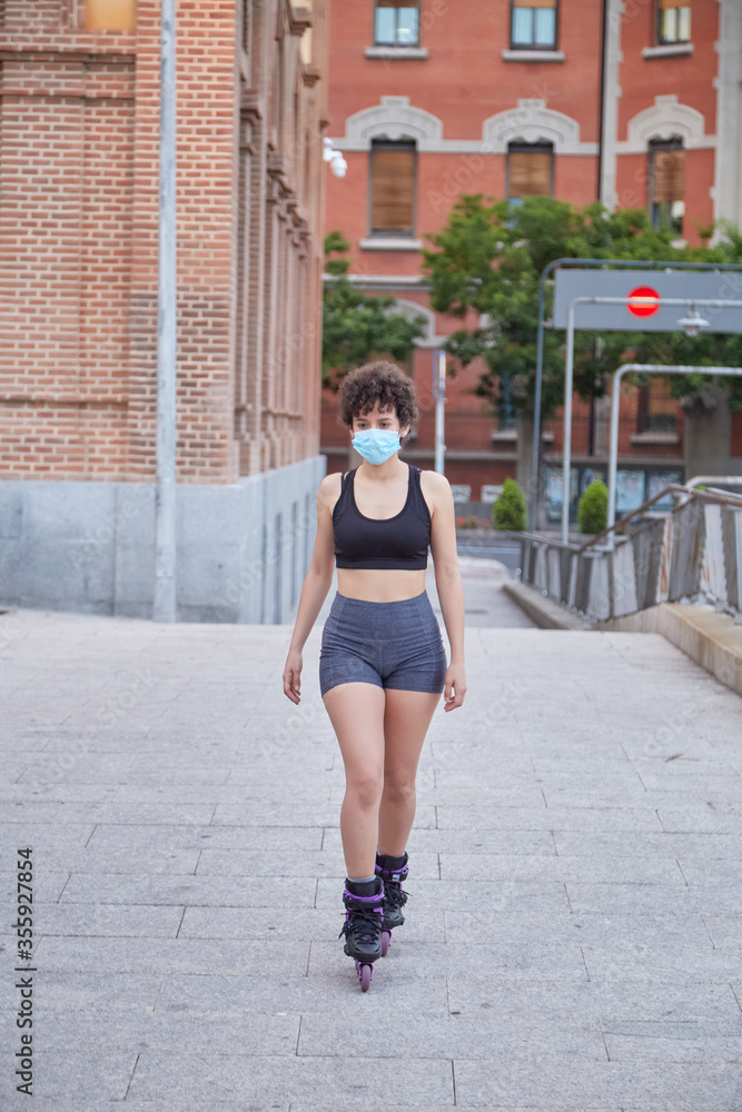 Latin girl skating on inline skates protecting herself with a face mask