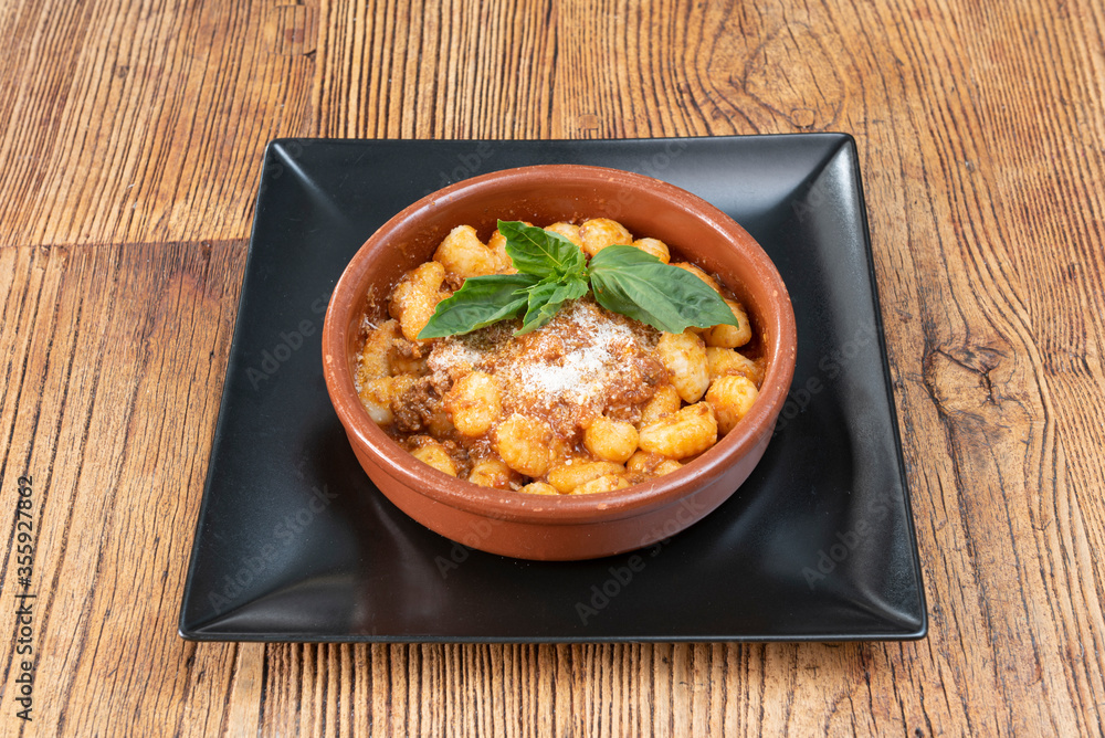 Gnocchi al ragu on dark wooden table Gnocchi al ragu on dark wooden table