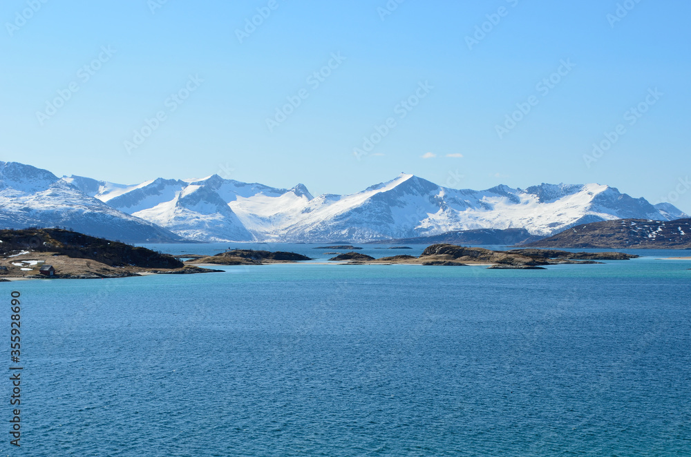 small settlement on sea islands with snowy mountains and sunshine