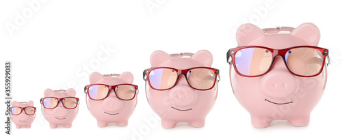 Cute piggy banks of different sizes on white background