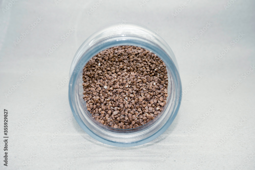 Buckwheat groats in a glass jar on a light background close-up. Healthy diet vegan food. Buckwheat groats in a glass jar on a light background close-up. Healthy diet vegan food.