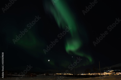 northern light on night sky with full moon and snowy field