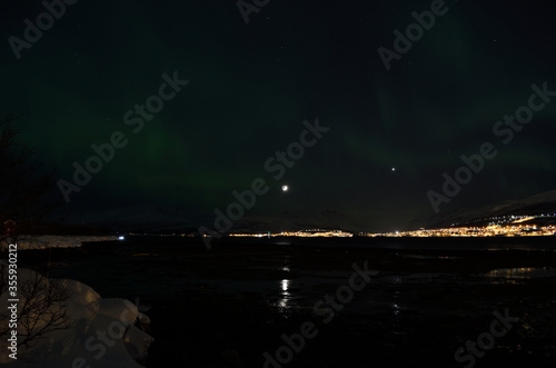 aurora borealis dancing over snowy mountain and fjord landscape with full moon light © Arcticphotoworks