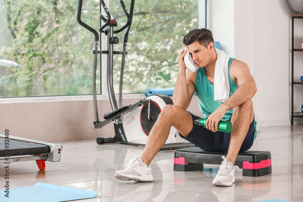 Sporty young man resting after training in gym Sporty young man resting after training in gym