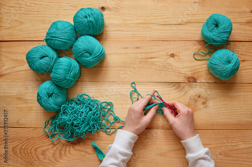 Female Hands Knitting With Turquoise Wool, On A Wooden Table, Top View