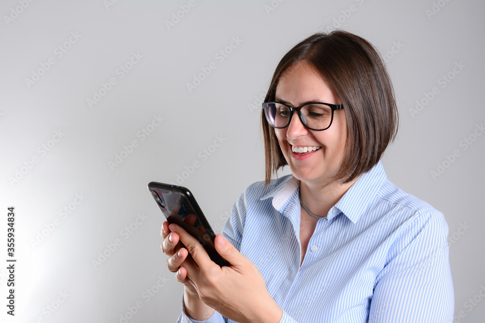 Gorgeous smiling woman looking at her mobile phone. Woman texting on her phone, isolated over white background.