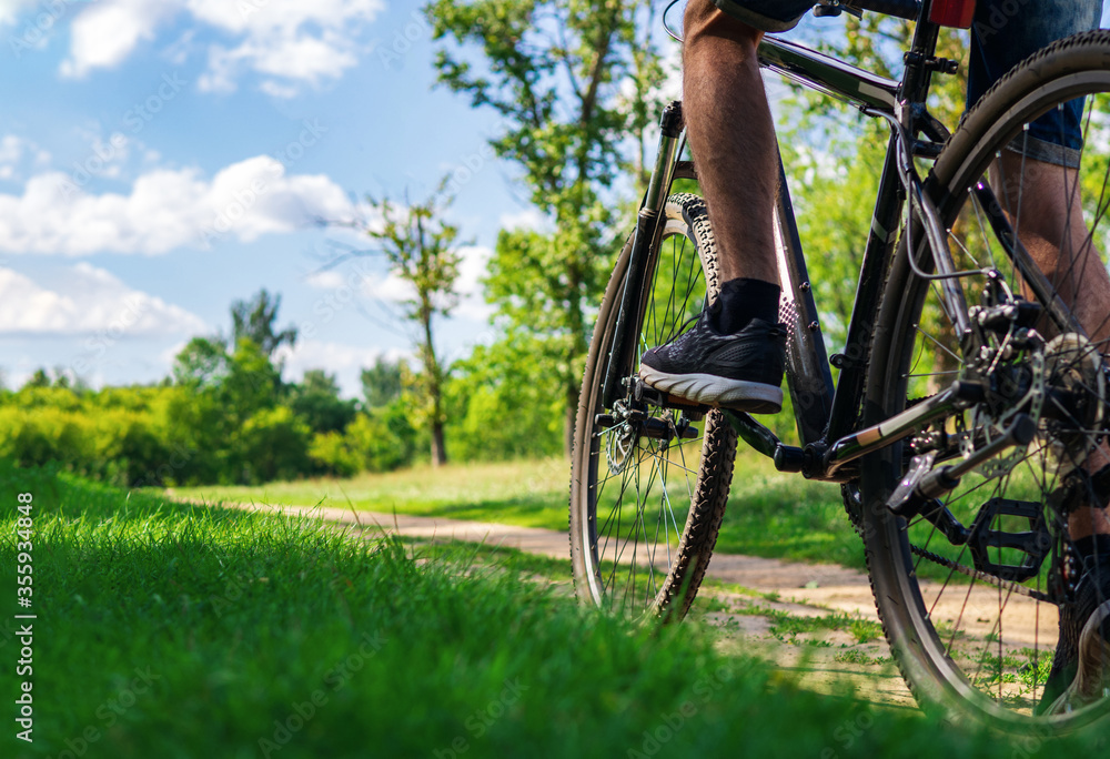 Naklejka premium A young man rides a Bicycle on country roads close up copy space