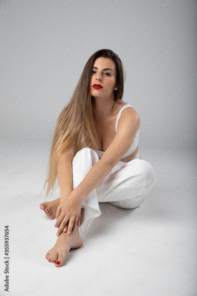 Modelo joven sentada sobre fondo blanco y ropa blanca con pelo largo Modelo joven sentada sobre fondo blanco y ropa blanca con pelo largo
