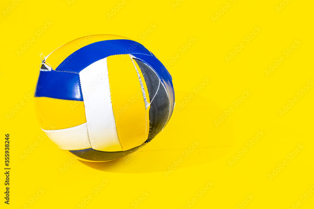 daylight. very bright sun. Retro yellow wooden background. The volleyball ball broke completely daylight. very bright sun. Retro yellow wooden background. The volleyball ball broke completely