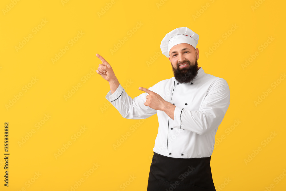 Handsome male chef pointing at something on color background Handsome male chef pointing at something on color background