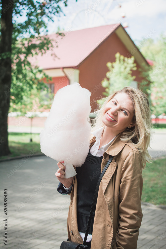 Naklejka premium Close up portrait of a smiling excited girl holding cotton candy at amusement park