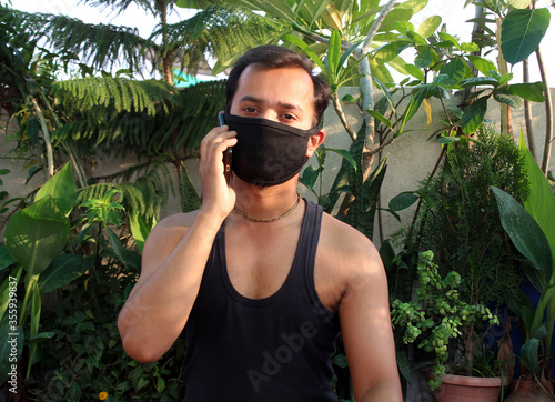 young man using mobile phone with wear protective mask on face