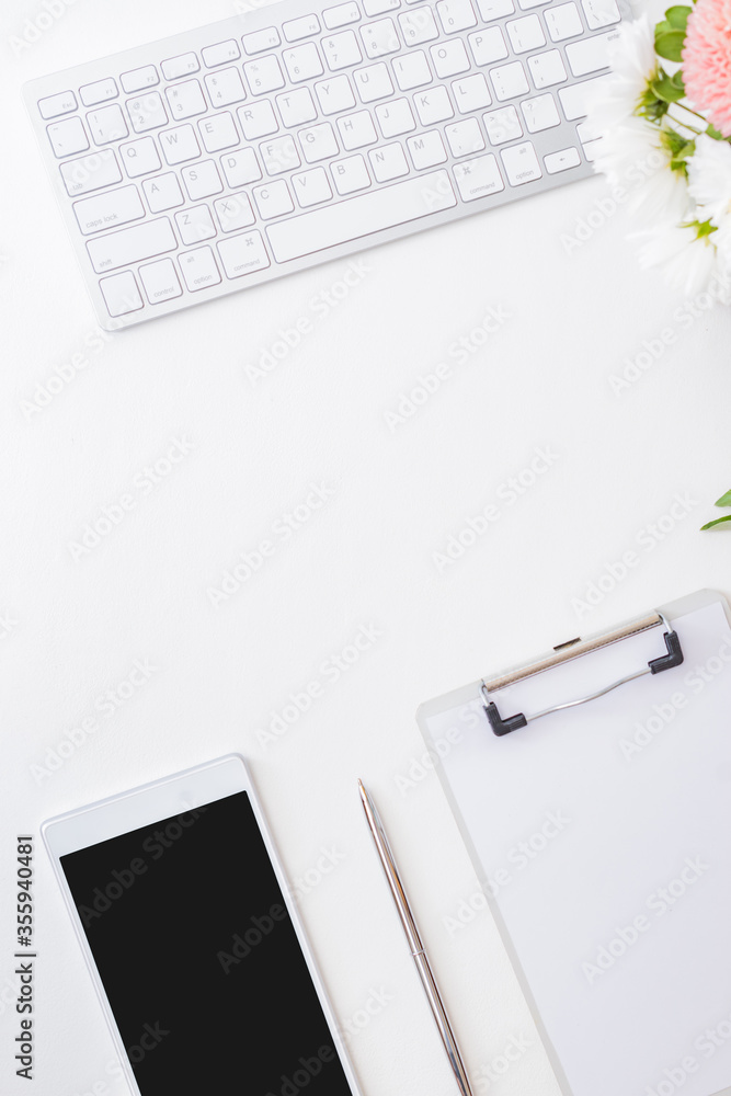 Flat lay blogger or freelancer workspace with a smartphone, clipboard, flowers in a vase, office supplies on a light background Flat lay blogger or freelancer workspace with a smartphone, clipboard, flowers in a vase, office supplies on a light background