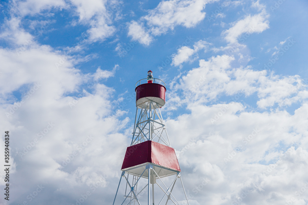 Red with white Lighthouse in Aurich Germany with blue sky with clouds