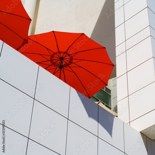 A red umbrella against a white stone wall.