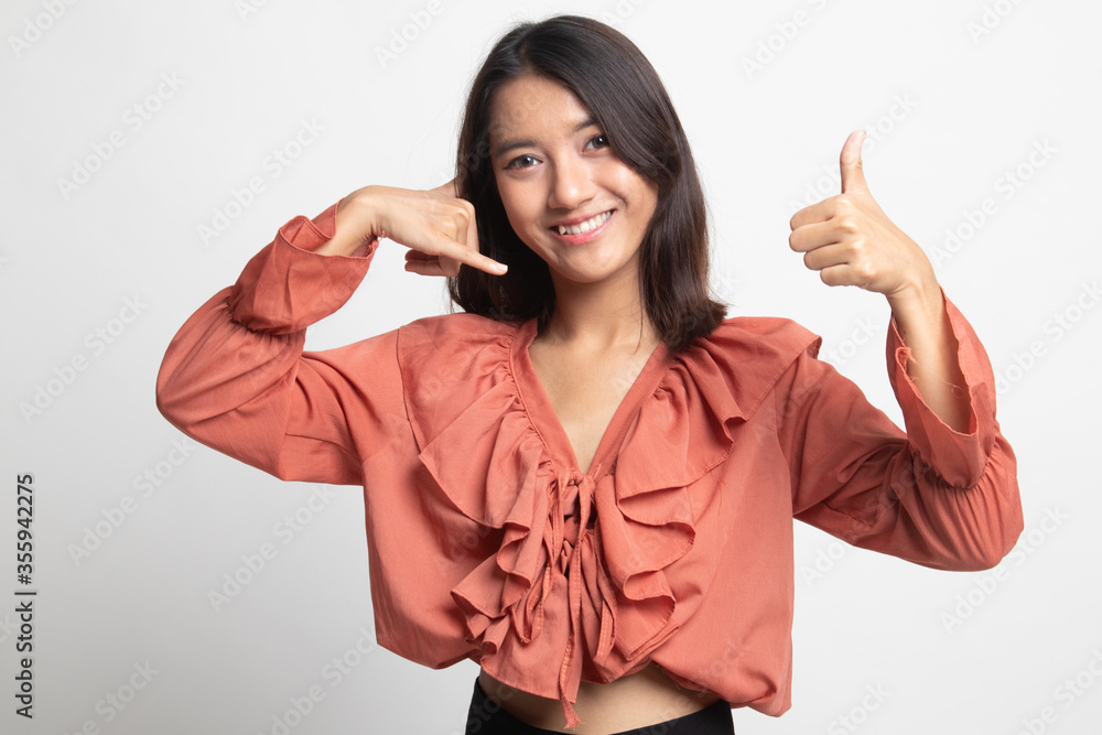 Young Asian woman thumbs up show with phone gesture . Young Asian woman thumbs up show with phone gesture .