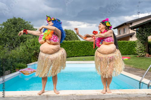 two female friends dressed in a Hawaiian costume have fun dancing