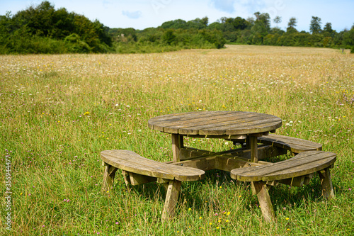 Wooden picnic table and chairs set in spring summer woodland country landscape