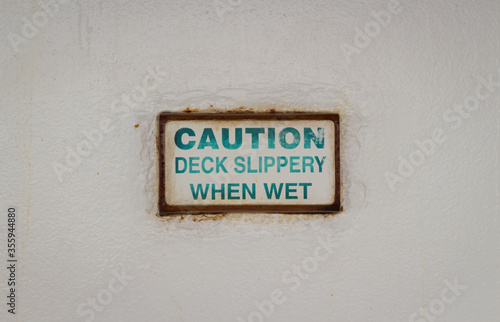 A slippery when wet caution sign outside on the deck of a cruise ship. © Hugo