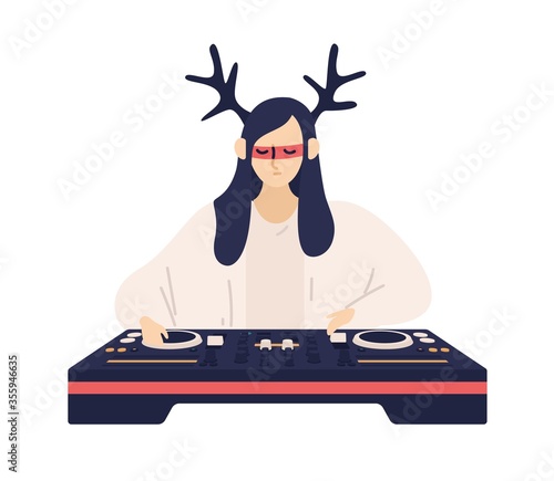 Fashionable female DJ in funny deer horns and glasses playing electronic musi...