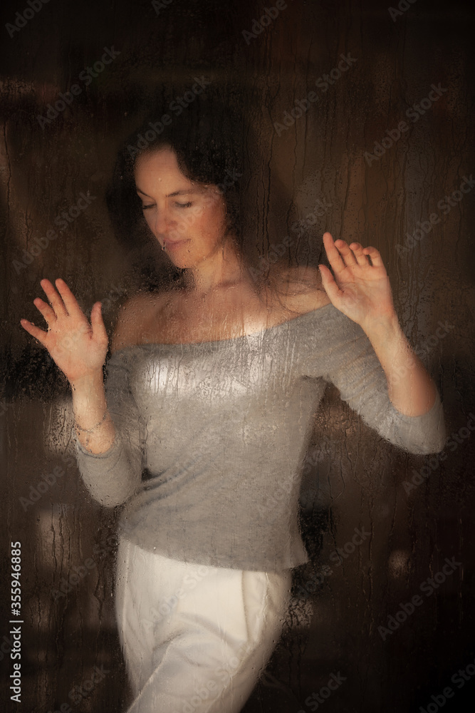 lonely woman near a glass during a pandemic
