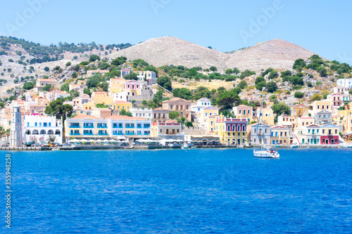 A lot of tiny colorful houses on the rocky shore of Mediterrenean sea on Simy greek island in sunny summer day, tourism on exotic islands © Sunny_Smile