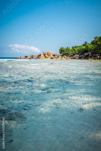portrait format of nice tropical sandy beach with famous granite rocks on Anse Coco beach, La Digue Island, Seychelles. Holiday and vacation concept. Tropical beach on background blue sky