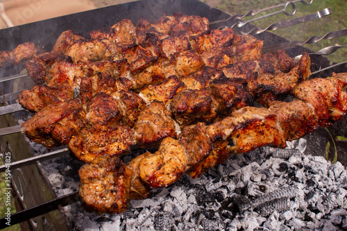 shish kebab in the open air on the grill.cooking meat on the street. street food. picnic. family rest. meat on the shampoo. heat from roast meat. heat from coals on the grill. Shish kebab from chicken