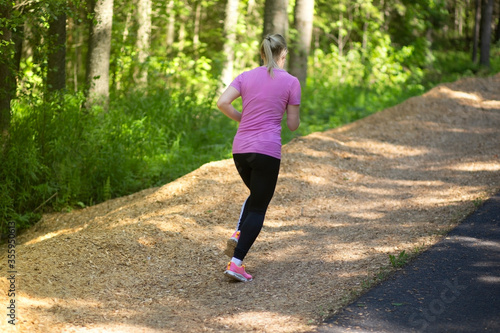 The girl is running on an asphalt road in the Park in the summer.