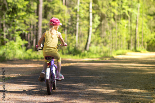 A girl rides a Bicycle on an asphalt road in the Park in the summer.