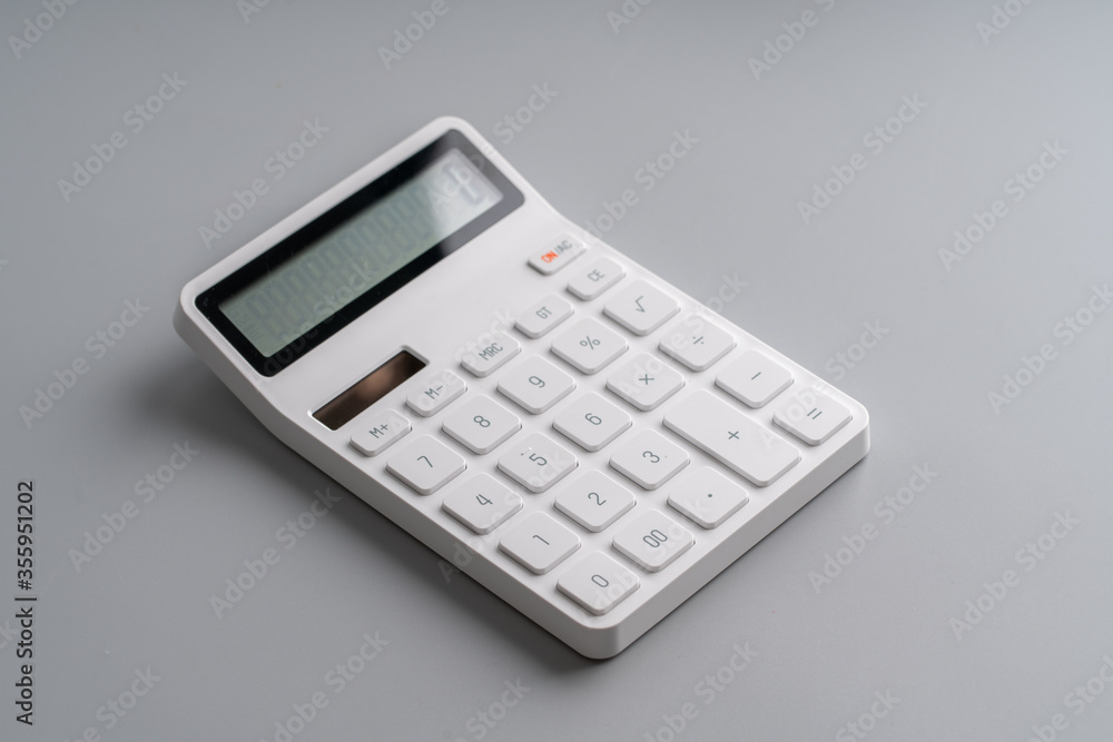 White calculator on grey background for education & business concept White calculator on grey background for education & business concept