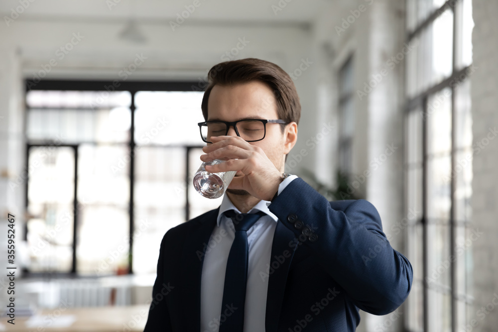 Thirsty young Caucasian businessman feel dehydrated drink pure clean still mineral water from glass, dehydrated male employee enjoy clear crystal aqua, refresh body, hydration, healthy life concept Thirsty young Caucasian businessman feel dehydrated drink pure clean still mineral water from glass, dehydrated male employee enjoy clear crystal aqua, refresh body, hydration, healthy life concept