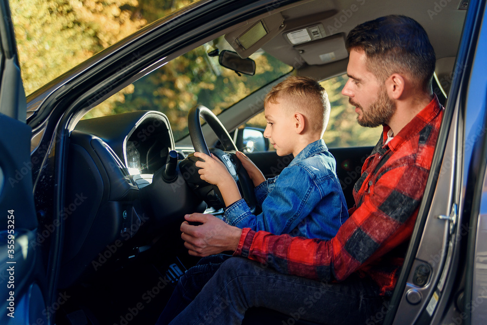 Obraz premium handsome father pointing on something while teaching teen son driving car