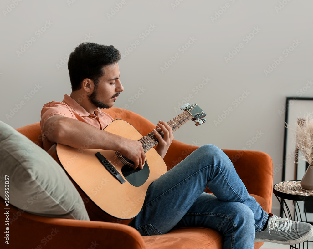 Handsome young man playing guitar at home - obrazy, fototapety, plakaty 