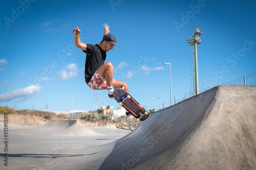 hombre joven hace un salto desde una rampa en un skate park. photo