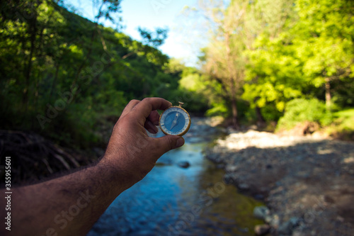 Traveler man holding a compass on river