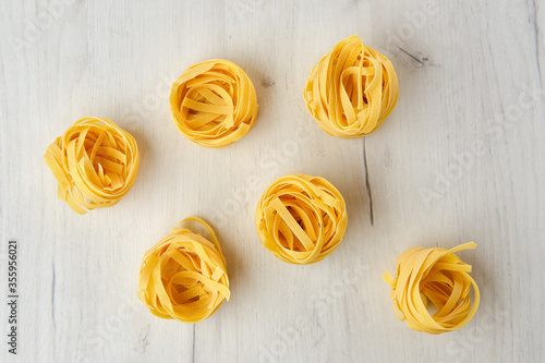 Overhead view of raw tagliatelle on wooden table