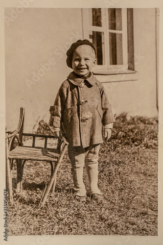 Latvia - CIRCA 1930s: Portrait of girl next to bench in garden. Vintage Art Deco era photography