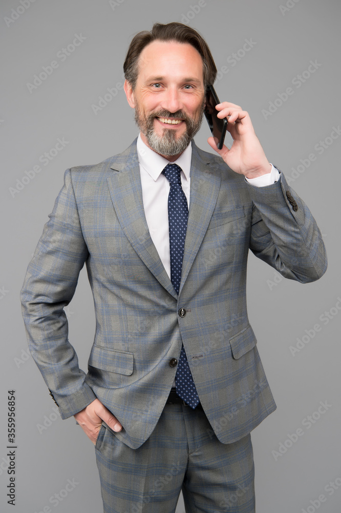 Naklejka premium mature boss talk on phone. man holding device and smiling. speak to colleague. technology bring success. successful businessman deal with problem online. agile business
