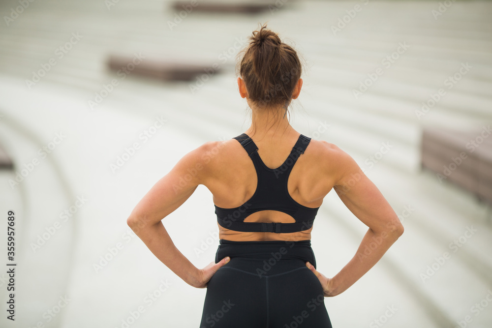 beautiful young woman in black sportswear is standing with her back