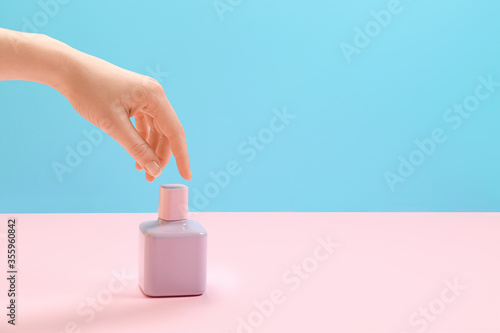 Female hand with perfume on color background