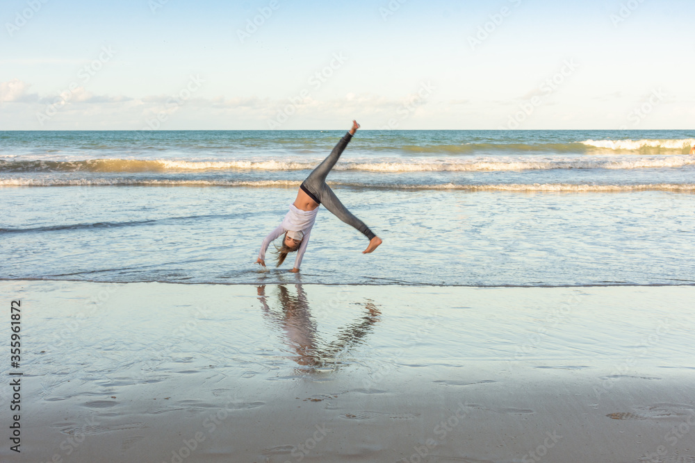 Masked young girl exercising on the beach with pirouettes Masked young girl exercising on the beach with pirouettes