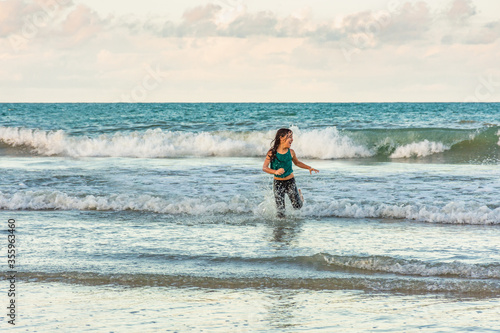 Child running in the water on the beach on a beautiful day