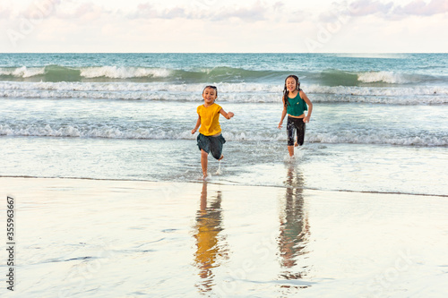 Children running in the water on the beach on a beautiful day