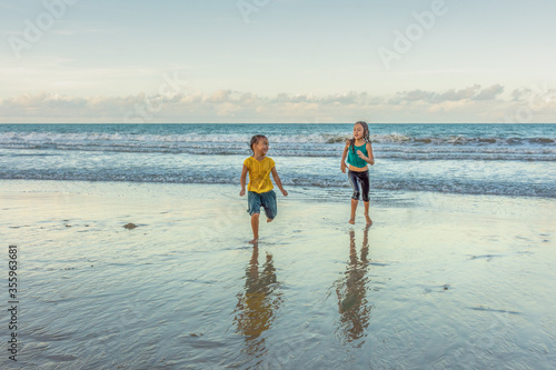 Children running in the water on the beach on a beautiful day